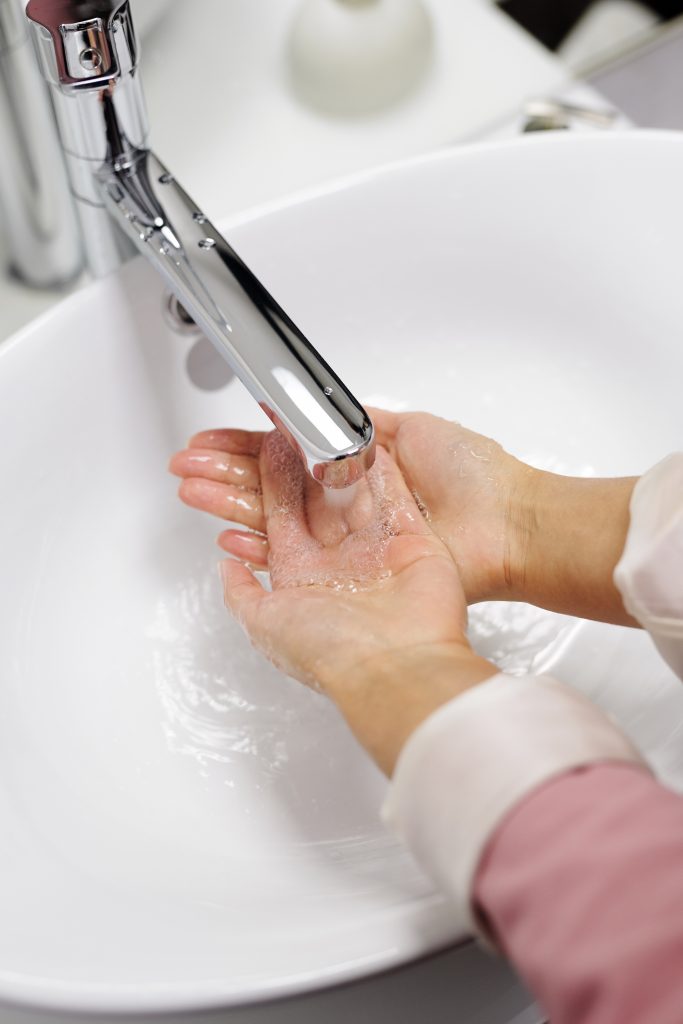 waschende Hände unter laufendem Wasserhahn